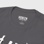 Charcoal heavyweight graphic tee featuring bold 'CHASE the HORIZN' print, worn by male model with long hair and distressed jeans, embodying modern moto culture.