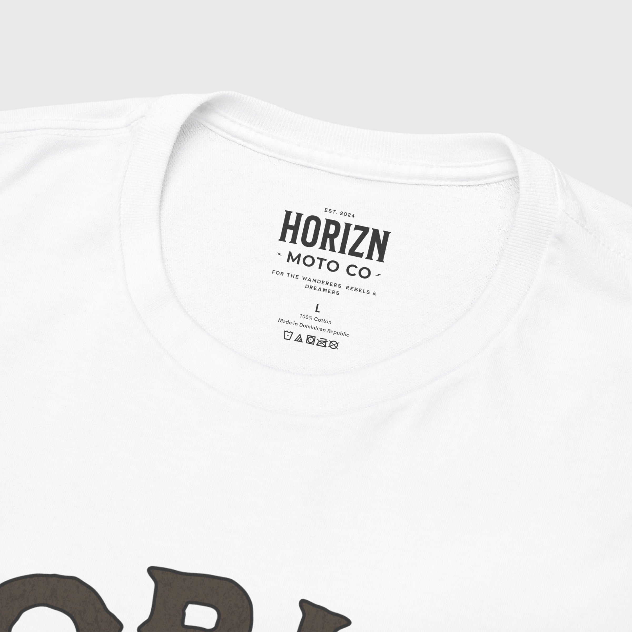 Chase the Coffee Moto Graphic Tee featuring a skeleton biker drinking coffee, worn by a man with long hair in a white t-shirt. Vintage moto design with radial line detailing on a clean white backdrop.