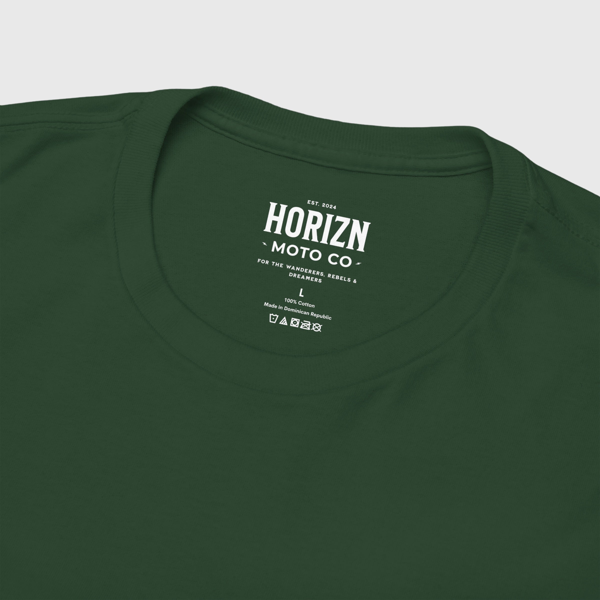 Man with a beard wearing a forest green Moto Culture Heavyweight T-Shirt featuring gold 'Horizon' script on the chest, styled with blue jeans.