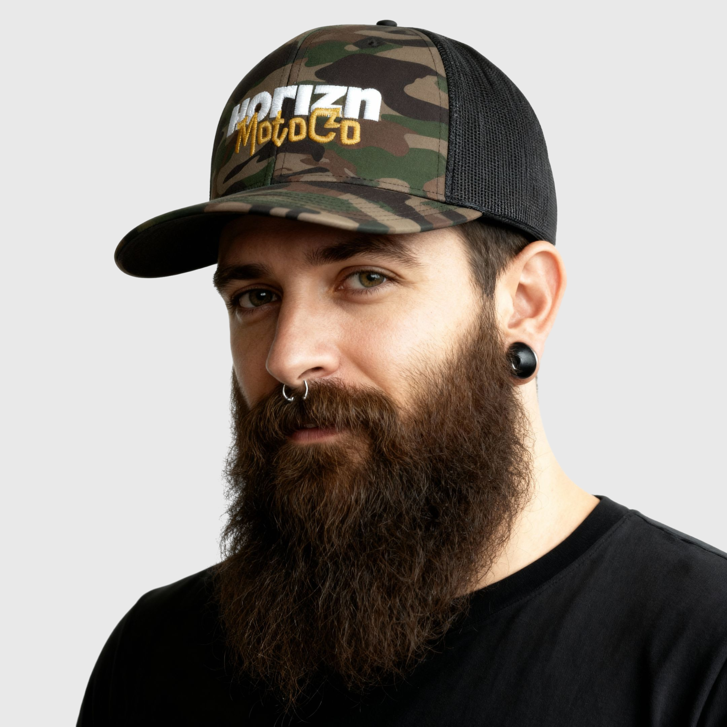 Camo Mesh Trucker Cap with white 'HORIZN' logo and gold 'MotoCo' graphic, designed for riders and city drifters, showcasing rugged style and breathable mesh panels.