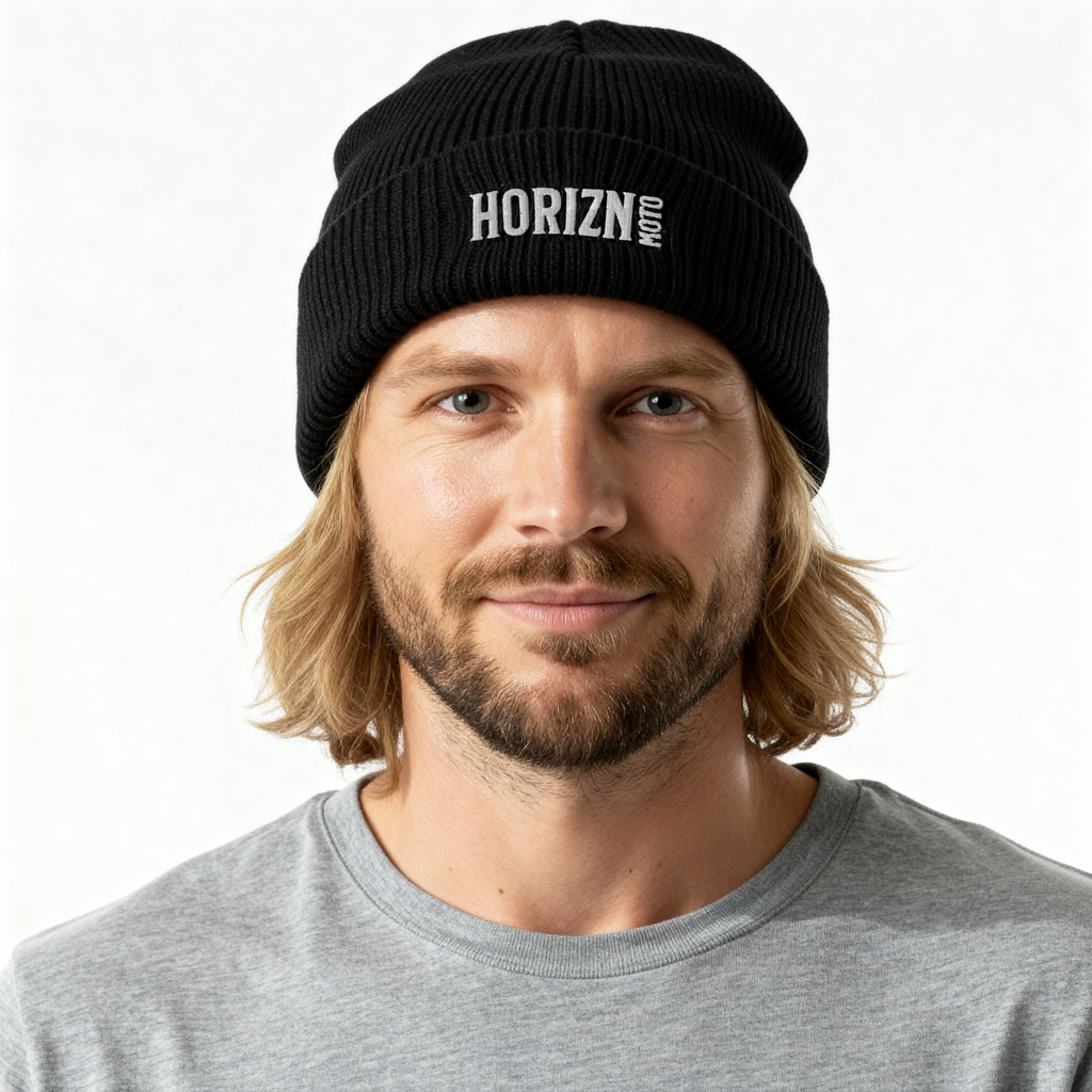 Black ribbed knit beanie with white HORIZN MOTO logo, worn by man with light blond hair and beard, showcasing a snug fit for colder rides.