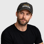 Model wearing the Multicam Black camouflage Chase the HORIZN Flexfit cap, showing the gold-and-white embroidered front and curved visor.